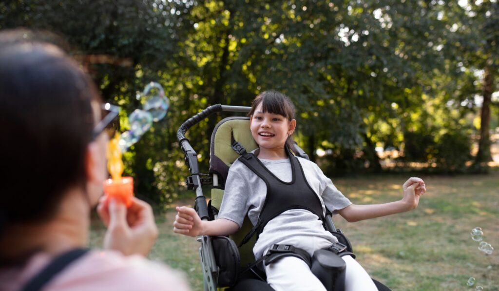 A photo of a young girl in a wheelchair enjoying bubbles outside
