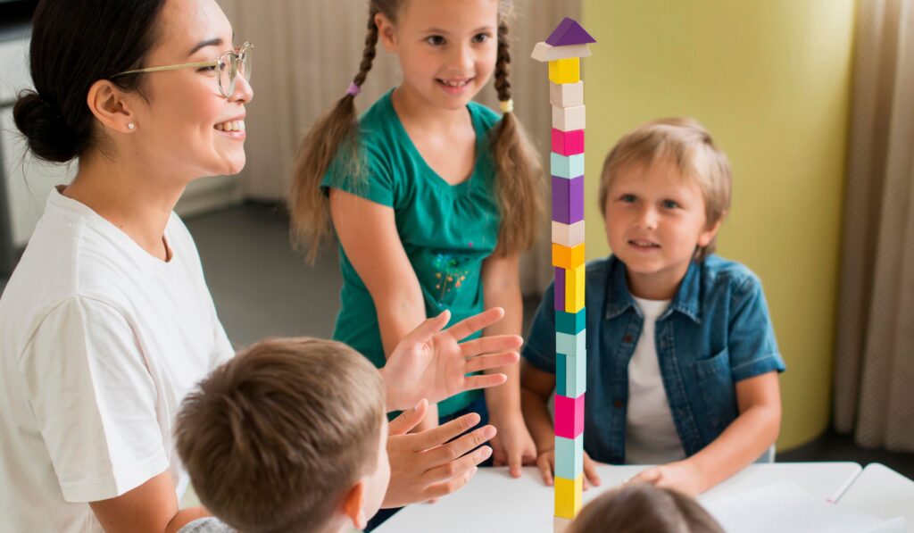 Images shows a female therapist stacking blocks with a group of students