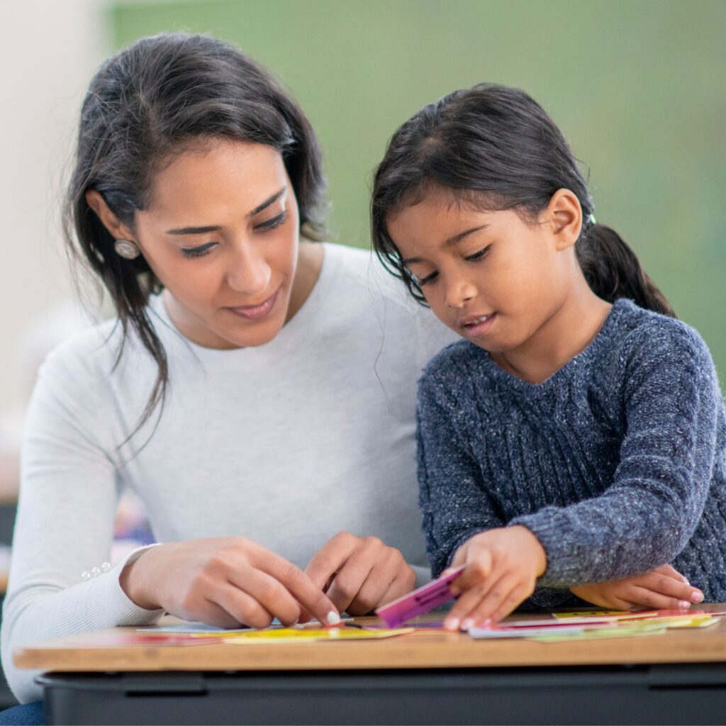 Image shows a teacher and student working together with a game.