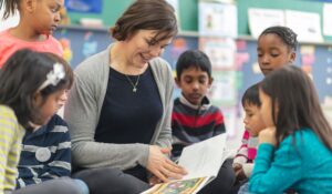 A teacher reading a book to a group of students