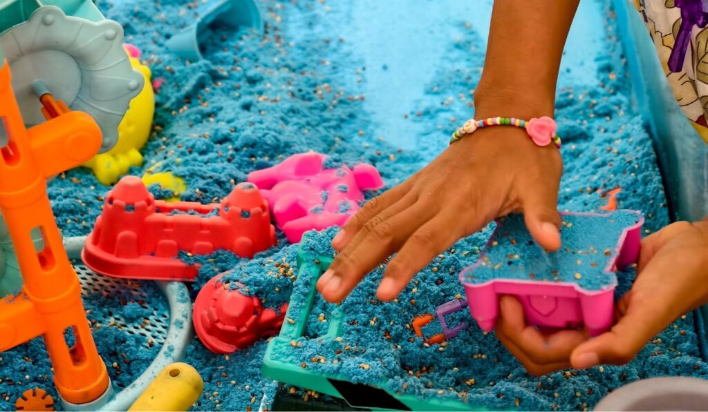 A young child playing in blue kinetic sand