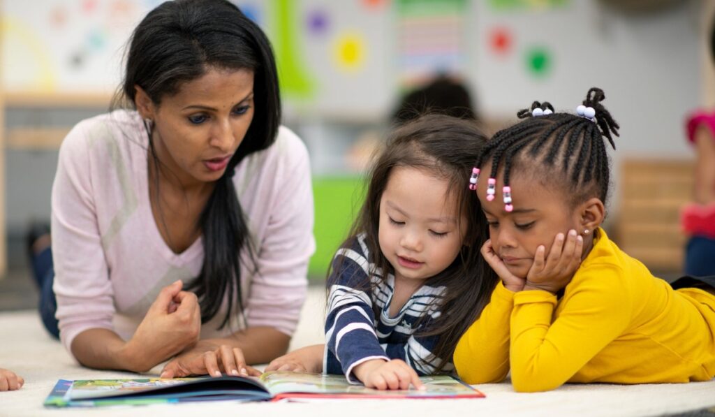 A teacher looking at a book with two children