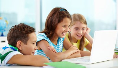 three students are looking at a laptop and smiling