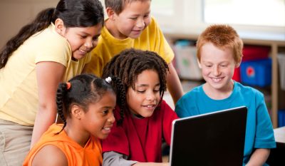 A group of students are looking at a laptop