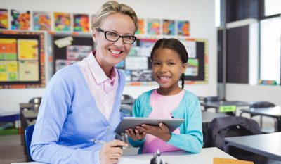 A teacher is helping a student with an activity on a tablet