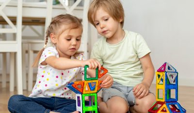 image shows two children playing with magnetic tiles