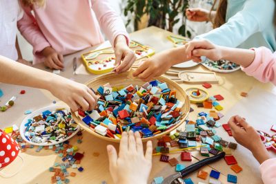 The mosaic puzzle art for kids, children's creative game. The hands are playing mosaic at table. Colorful multi-colored details close up. Creativity, children's development and learning concept